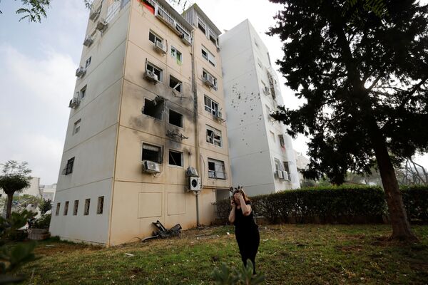 Người phụ nữ cạnh tòa nhà dân bị hư hại ở Ashkelon do tên lửa phóng từ Dải Gaza  - Sputnik Việt Nam