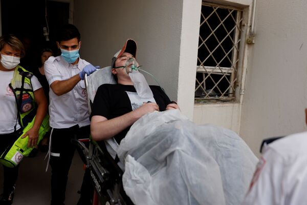 Các nhân viên y tế Israel sơ tán người đàn ông bị thương do tên lửa phóng từ Dải Gaza rơi trúng tòa nhà dân ở Ashkelon, miền nam Israel - Sputnik Việt Nam
