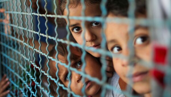 Trẻ em Palestine phải ra khỏi nhà bởi các cuộc không kích và pháo binh của Israel đang nhìn qua lan can cửa sổ của trường học do Liên hợp quốc điều hành, nơi họ trú ẩn ở thành phố Gaza - Sputnik Việt Nam