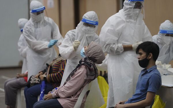 Nhân viên y tế thu thập mẫu từ người dân trong quá trình xét nghiệm coronavirus tại trung tâm xét nghiệm COVID-19 ở Ulu Klang, ngoại ô Kuala Lumpur, Malaysia. - Sputnik Việt Nam