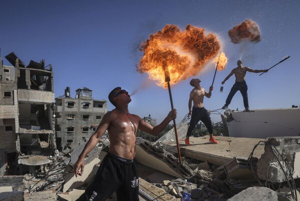 Các thành viên đội Bar Woolf của Palestine đến từ Gaza với màn trình diễn lửa trên đống đổ nát của một tòa nhà bị phá hủy bởi các cuộc không kích của Israel - Sputnik Việt Nam