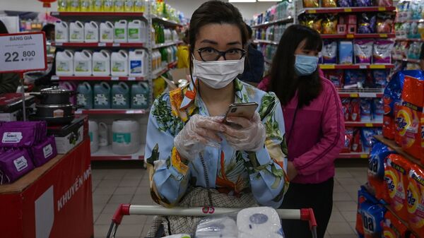 Cô gái đeo khẩu trang và găng tay đứng xếp hàng trong siêu thị Hà Nội. - Sputnik Việt Nam