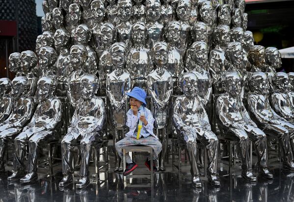 Cậu bé ngồi trên ghế giữa các tác phẩm điêu khắc được trưng bày tại một trung tâm thương mại vào Ngày Quốc tế Thiếu nhi ở Bắc Kinh - Sputnik Việt Nam