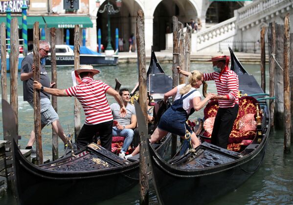 Những người chèo thuyền giúp khách du lịch ngồi xuống thuyền gondola, Venice - Sputnik Việt Nam