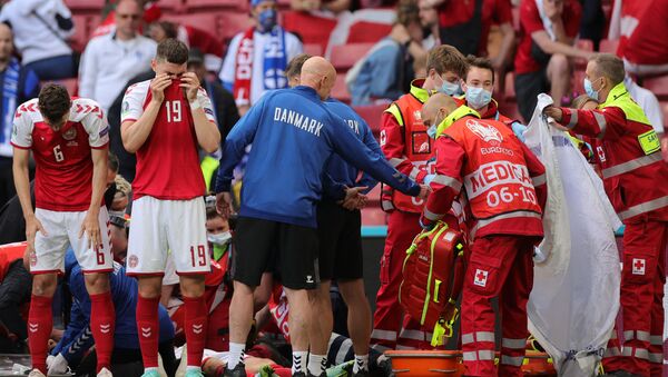 Denmark's players react as paramedics attend to Denmark's midfielder Christian Eriksen after he collapsed on the pitch during the UEFA EURO 2020 Group B football match between Denmark and Finland at the Parken Stadium in Copenhagen on June 12, 2021. - Sputnik Việt Nam