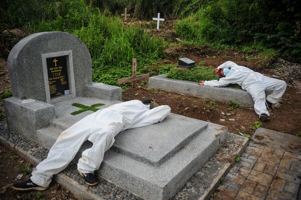 Công nhân mặc đồ bảo hộ nghỉ ngơi sau khi chôn cất nạn nhân nhiễm coronavirus (COVID-19) ở Bandung, Indonesia - Sputnik Việt Nam