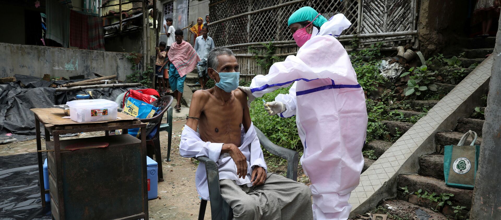 Motiar Rahman, một người dân trong làng, nhận một liều vắc-xin COVISHIELD, vắc-xin phòng bệnh do coronavirus (COVID-19) do Viện Huyết thanh của Ấn Độ sản xuất, trong một đợt tiêm chủng và thử nghiệm tận nhà tại Đảo Uttar Batora ở quận Howrah ở Tây Bengal bang, Ấn Độ, ngày 21 tháng 6 năm 2021. - Sputnik Việt Nam, 1920, 24.06.2021
