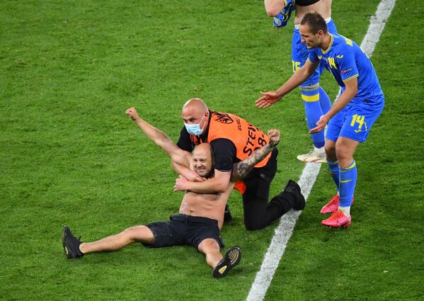 Nhân viên an ninh với một người đàn ông chạy vào sân trong trận Thụy Điển-Ukraina tại UEFA EURO 2020 - Sputnik Việt Nam