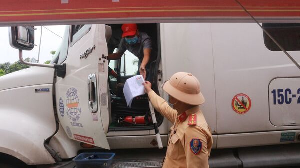 Cảnh sát giao thông công an thành phố Uông Bí (Quảng Ninh) kiểm tra các thủ tục của lái xe container trước khi qua chốt cầu Đá Bạc - Sputnik Việt Nam