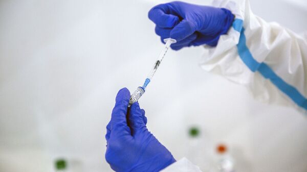 Một nhân viên y tế với một ống vắc xin Sputnik V khi tiêm chủng COVID-19 - Sputnik Việt Nam