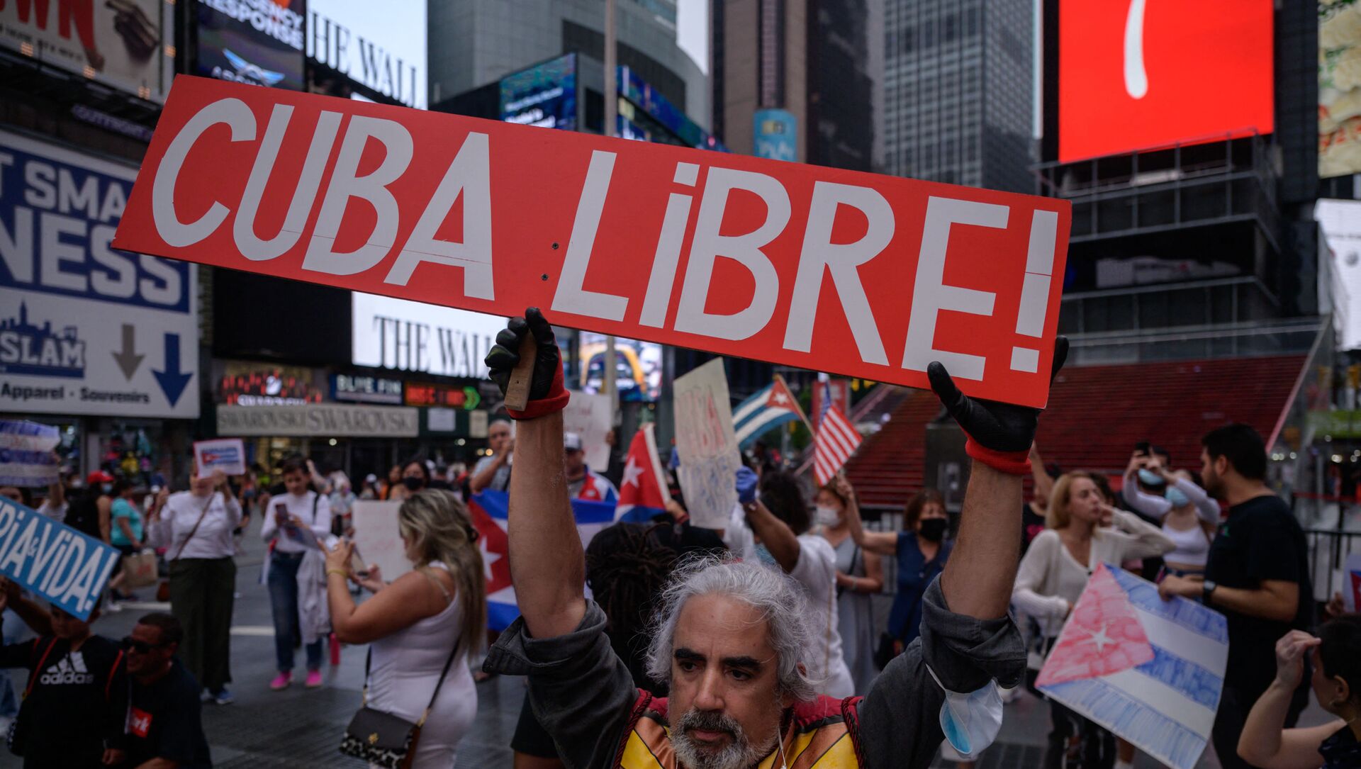 Người biểu tình cầm biểu ngữ trong một cuộc mít tinh được tổ chức đoàn kết với các cuộc biểu tình chống chính phủ ở Cuba, tại Quảng trường Thời đại, New York vào ngày 13 tháng 7 năm 2021. - Một người chết và hơn 100 người khác, bao gồm các nhà báo độc lập và nhà bất đồng chính kiến, đã bị bắt sau khi chưa từng có tiền lệ Các nhà quan sát và các nhà hoạt động cho biết các cuộc biểu tình chống chính phủ ở Cuba, với một số người còn lại bị giam giữ hôm thứ Ba. - Sputnik Việt Nam, 1920, 20.07.2021