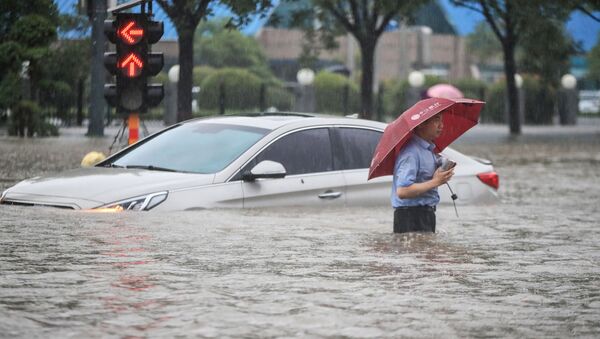 Người đàn ông trên chiếc ô tô bị ngập trong nước mưa xối xả sau đợt mưa lớn ở Trịnh Châu, tỉnh Hà Nam, miền Trung Trung Quốc - Sputnik Việt Nam