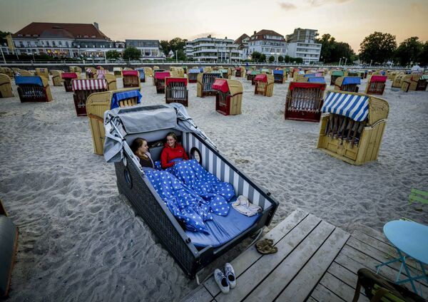 Hai cô gái chuẩn bị nghỉ đêm trên chiếc ghế tắm nắng được thiết kế đặc biệt trên bãi biển Baltic Sea ở Travemunde, Đức - Sputnik Việt Nam