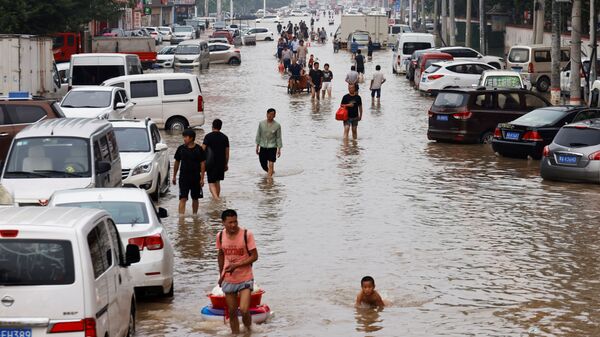 Người dân băng qua dòng nước lũ sau trận mưa lớn ở Trịnh Châu, tỉnh Hà Nam, Trung Quốc - Sputnik Việt Nam