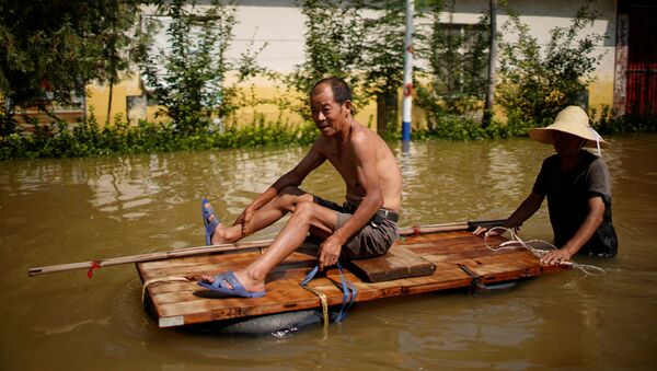 Dân làng băng qua dòng nước lũ sau trận mưa lớn tại một ngôi làng ở Tân Hương, tỉnh Hà Nam, Trung Quốc - Sputnik Việt Nam