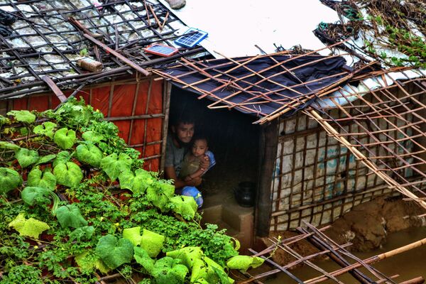Người đàn ông tị nạn với một đứa trẻ trong nơi trú ẩn bị ngập lụt sau trận mưa lớn tại trại tị nạn của người Rohingya ở Kutupalong, Bangladesh - Sputnik Việt Nam