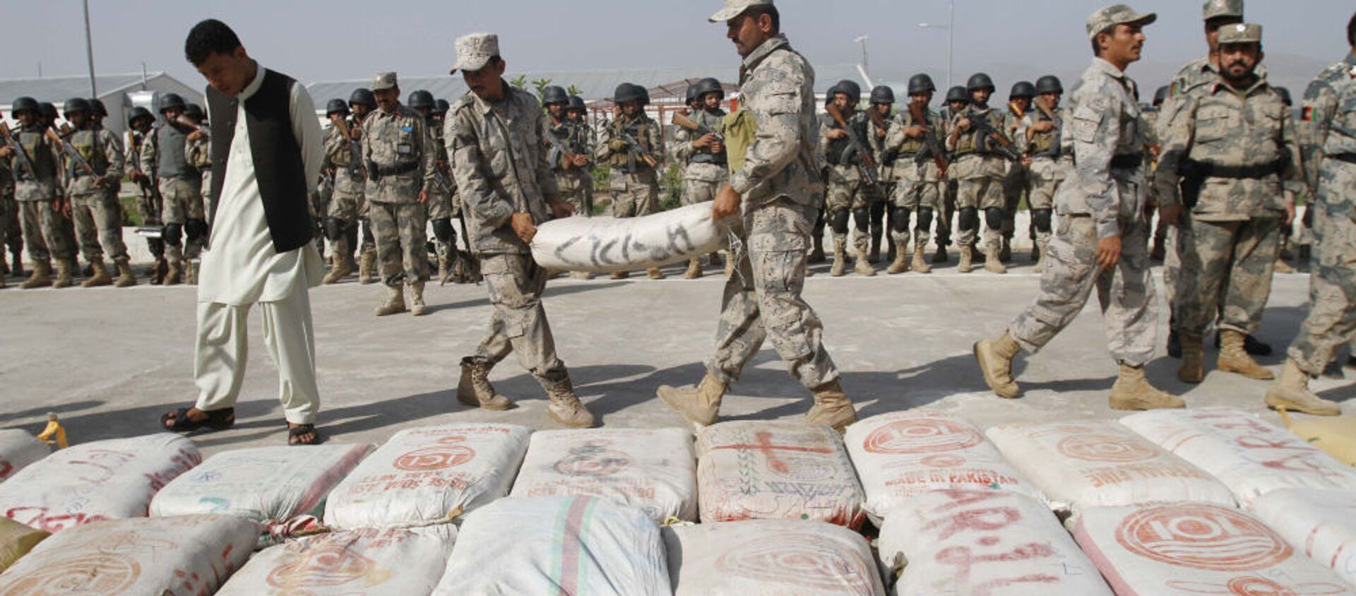 Các nhân viên Cảnh sát Biên giới Afghanistan mang một túi băm đến phần còn lại của số ma túy bị thu giữ tại một đồn cảnh sát ở Jalalabad, Afghanistan. - Sputnik Việt Nam, 1920, 03.08.2021
