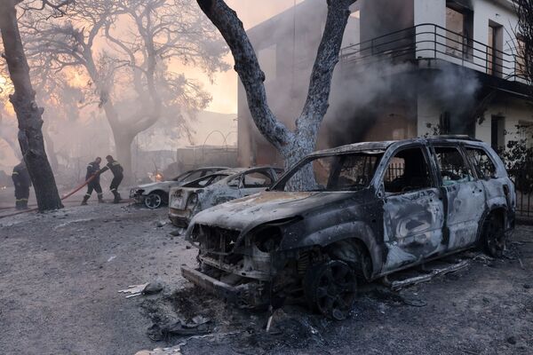Lính cứu hỏa làm việc gần những chiếc xe bị thiêu rụi trong trận cháy rừng ở ngoại ô Varympompi, phía bắc Athens, Hy Lạp - Sputnik Việt Nam