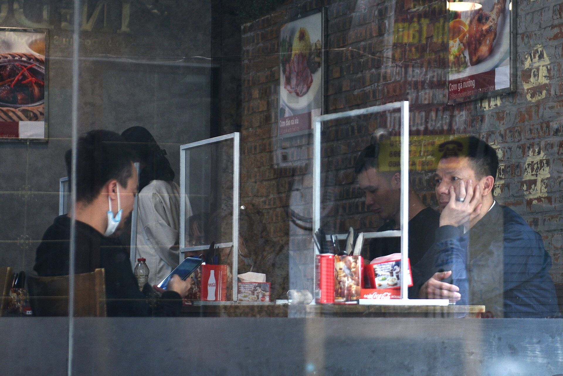 Thực khách ở Hà Nội ngồi trong nhà hàng sau tấm chắn nhựa chống coronavirus lây lan - Sputnik Việt Nam, 1920, 05.10.2021