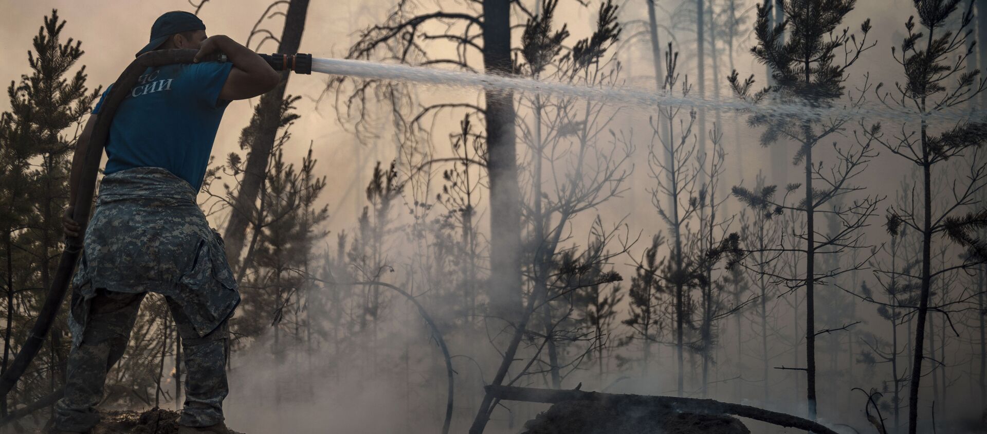 Một nhân viên của Bộ Tình trạng Khẩn cấp của Liên bang Nga trong khi dập tắt đám cháy rừng ở Yakutia - Sputnik Việt Nam, 1920, 10.08.2021