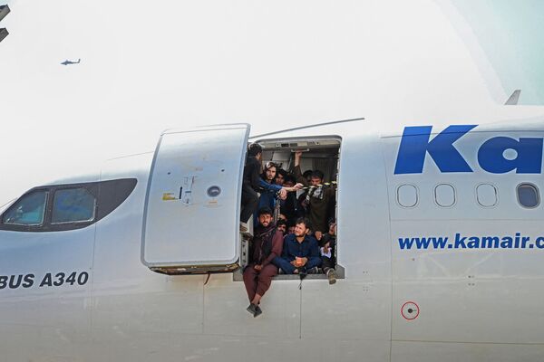Người dân Afghan ngồi ở cửa máy bay tại phi trường Kabul - Sputnik Việt Nam