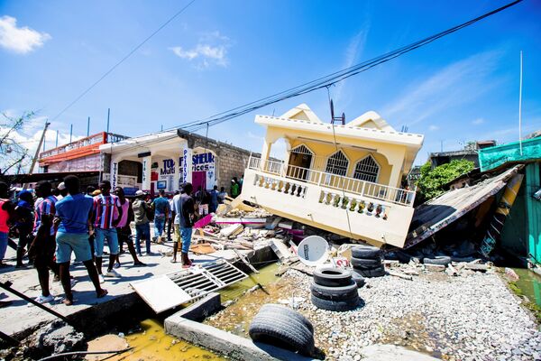 Người dân cạnh ngôi nhà bị phá hủy bởi trận động đất 7,2 độ richter ở Le Quay, Haiti - Sputnik Việt Nam