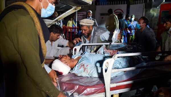 Nhân viên y tế đang khiêng một người đàn ông bị thương trên cáng để hỗ trợ y tế sau hai vụ nổ ở sân bay Kabul - Sputnik Việt Nam