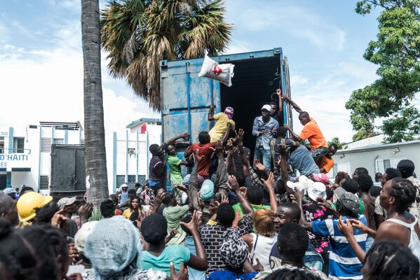 Người đàn ông ném bao gạo vào đám đông khi đang phân phát thức ăn và nước uống cho các nạn nhân động đất ở Le Quay, Haiti - Sputnik Việt Nam