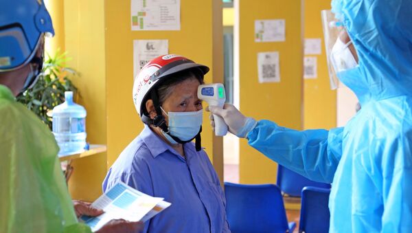 Đo thân nhiệt cho nhân dân đến tiêm vaccine tại bệnh viện Dệt may. - Sputnik Việt Nam