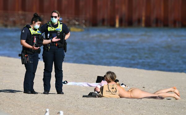 Cảnh sát nói chuyện với người phụ nữ tắm nắng trên bãi biển St Kilda ở Melbourne trong quá trình cách ly - Sputnik Việt Nam