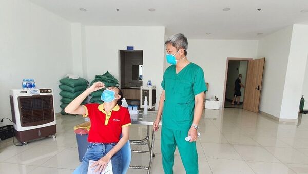 Thứ trưởng Bộ Y tế Nguyễn Trường Sơn quan sát việc hướng dẫn người dân tự xét nghiệm nhanh tại nhà. - Sputnik Việt Nam