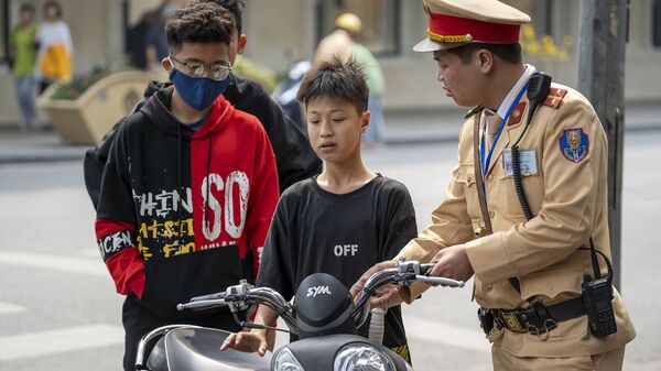 Cảnh sát Việt Nam chặn một cậu bé điều khiển xe máy vì vi phạm luật lệ giao thông trên phố cổ Hà Nội, Việt Nam. - Sputnik Việt Nam
