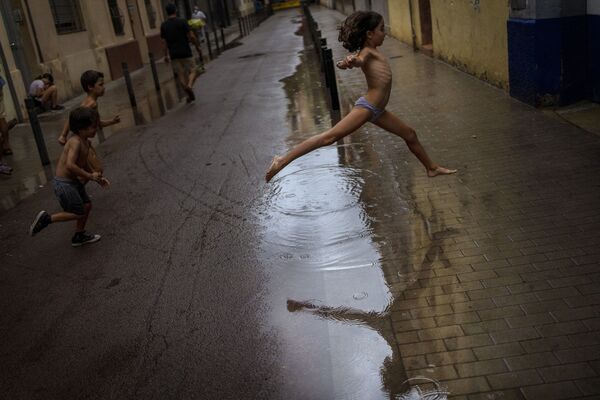 Bọn trẻ nhảy qua vũng nước trong mưa ở Barcelona, Tây Ban Nha - Sputnik Việt Nam