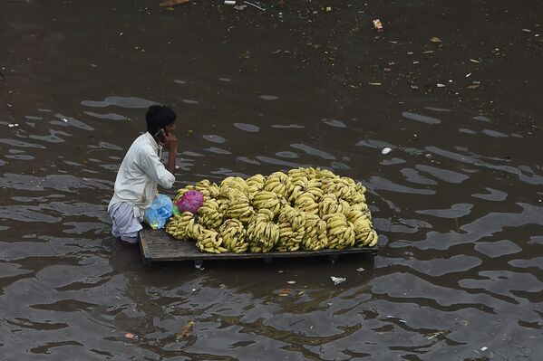 Người bán trái cây với chiếc xe đẩy trên đường phố ngập lụt sau trận mưa lớn ở Lahore, Pakistan - Sputnik Việt Nam