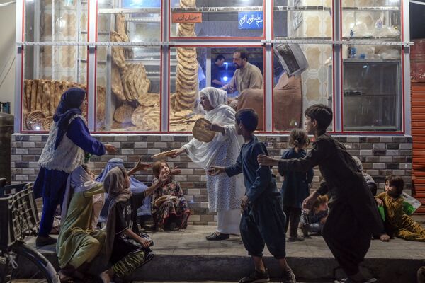 Người phụ nữ phân phát bánh mì cho trẻ em nghèo trước tiệm bánh ở Kabul - Sputnik Việt Nam