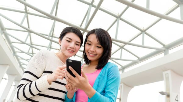 Hai cô gái châu Á nhìn vào điện thoại thông minh - Sputnik Việt Nam