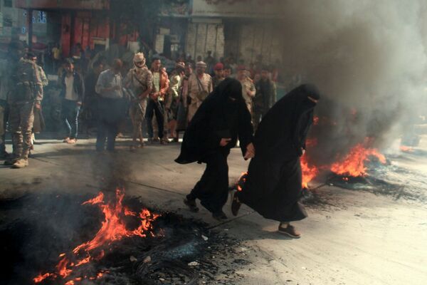 Những người phụ nữ chạy qua đám lốp xe đang cháy trong cuộc biểu tình ở Taiz, Yemen - Sputnik Việt Nam