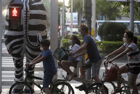 Những người đi xe đạp đeo khẩu trang gần cột đèn giao thông hình ngựa vằn ở Đài Bắc, Đài Loan - Sputnik Việt Nam