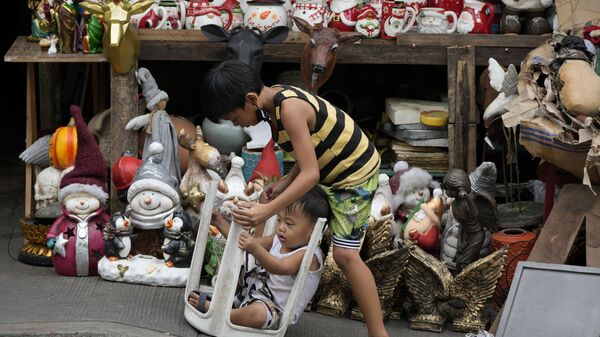Bọn trẻ chơi đùa bên những món đồ trang trí Giáng sinh bày bán trên con phố ở Manila, Philippines - Sputnik Việt Nam