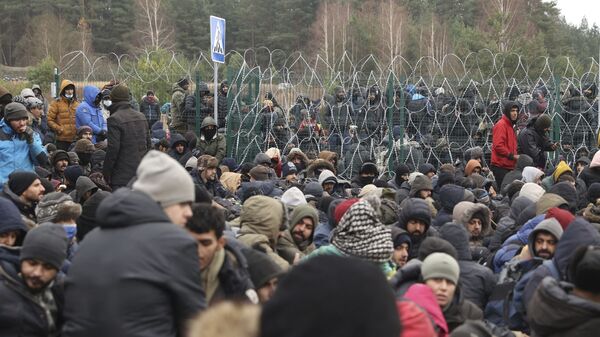 Người di cư trước hàng rào dây thép gai ở trạm kiểm soát Kuznitsa tại biên giới Belarus-Ba Lan - Sputnik Việt Nam