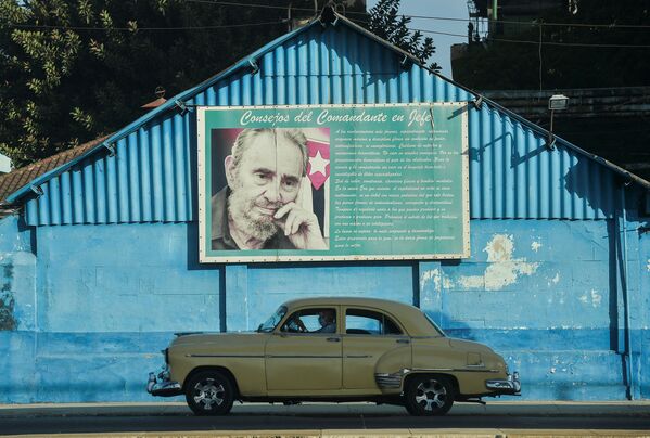 Chiếc ô tô cũ của Mỹ dưới tấm băng rôn lớn với chân dung cựu lãnh đạo Cuba Fidel Castro ở Havana, năm 2021 - Sputnik Việt Nam
