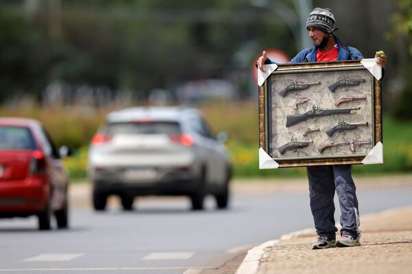 Người di cư Colombia cầm chiếc khung gắn vũ khí giả cổ đi bán trên con phố ở Brasilia - Sputnik Việt Nam