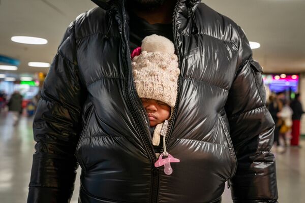 Người đàn ông ôm đứa con nhỏ trong áo khoác tại ga Pennsylvania, New York. - Sputnik Việt Nam