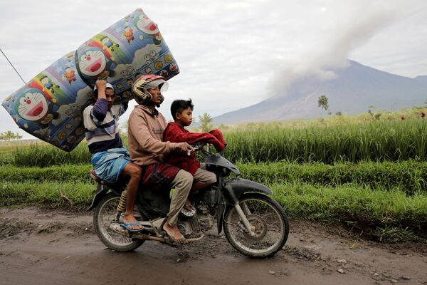 Người dân vận chuyển một tấm nệm trong bối cảnh núi lửa Semeru đang phun trào ở Indonesia - Sputnik Việt Nam