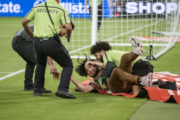 Nhân viên bảo vệ bắt giữ một cổ động viên chạy ào vào sân sau trận bóng giao hữu quốc tế giữa Mexico và Chile - Sputnik Việt Nam