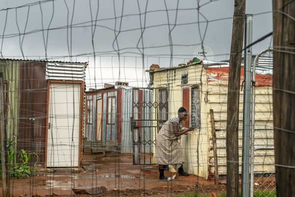 Người phụ nữ đóng cửa sổ trong nhà tại khu định cư không chính thức ở ngoại ô Johannesburg, Nam Phi - Sputnik Việt Nam