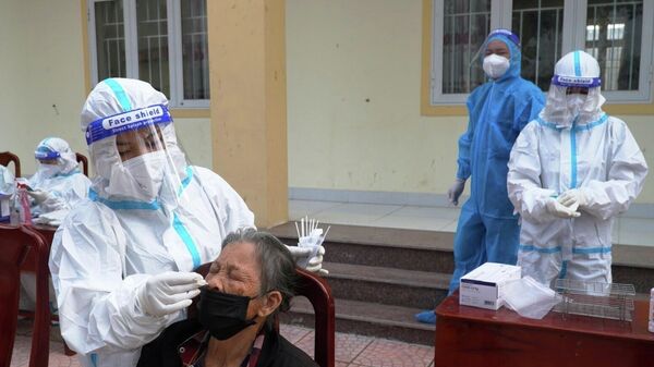 Lực lượng y tế địa phương tiến hành xét nghiệm lấy mẫu sàng lọc trong cộng đồng tại khu vực liên quan đến ca bệnh F0 mới phát hiện. - Sputnik Việt Nam