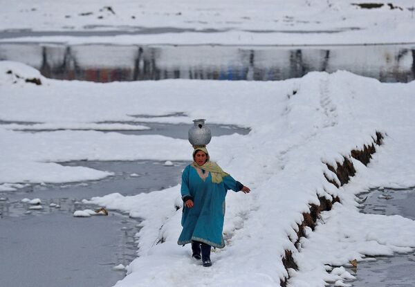 Người phụ nữ đội bình nước trên đầu trên cánh đồng phủ đầy tuyết ở ngoại ô thành phố Srinagar, Ấn Độ - Sputnik Việt Nam