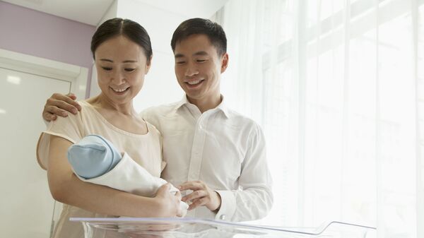 Một gia đình trẻ hạnh phúc ôm một em bé - Sputnik Việt Nam