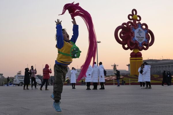 Đứa trẻ chơi với chiếc khăn quàng đỏ ở Quảng trường Thiên An Môn ở Bắc Kinh trong khung cảnh trang trí cho Thế vận hội Olympic - Sputnik Việt Nam